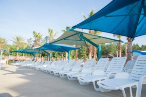 Image of poolside lounge chairs covered by shade structures